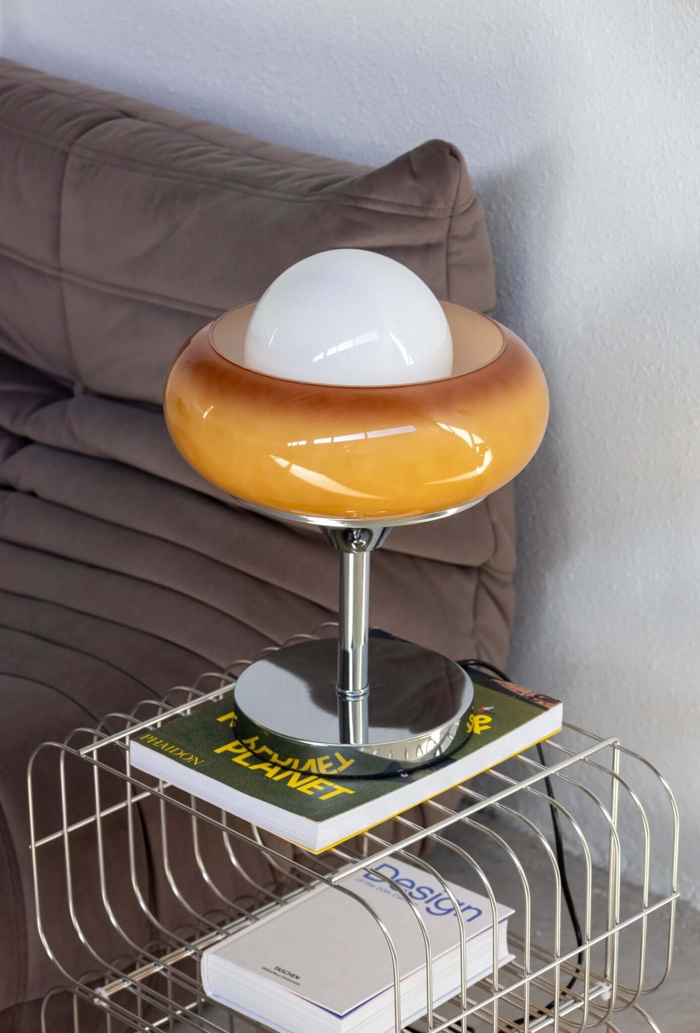 Retro lamp with an amber shade and white globe, styled on a side table with books, adding vintage charm to modern decor.