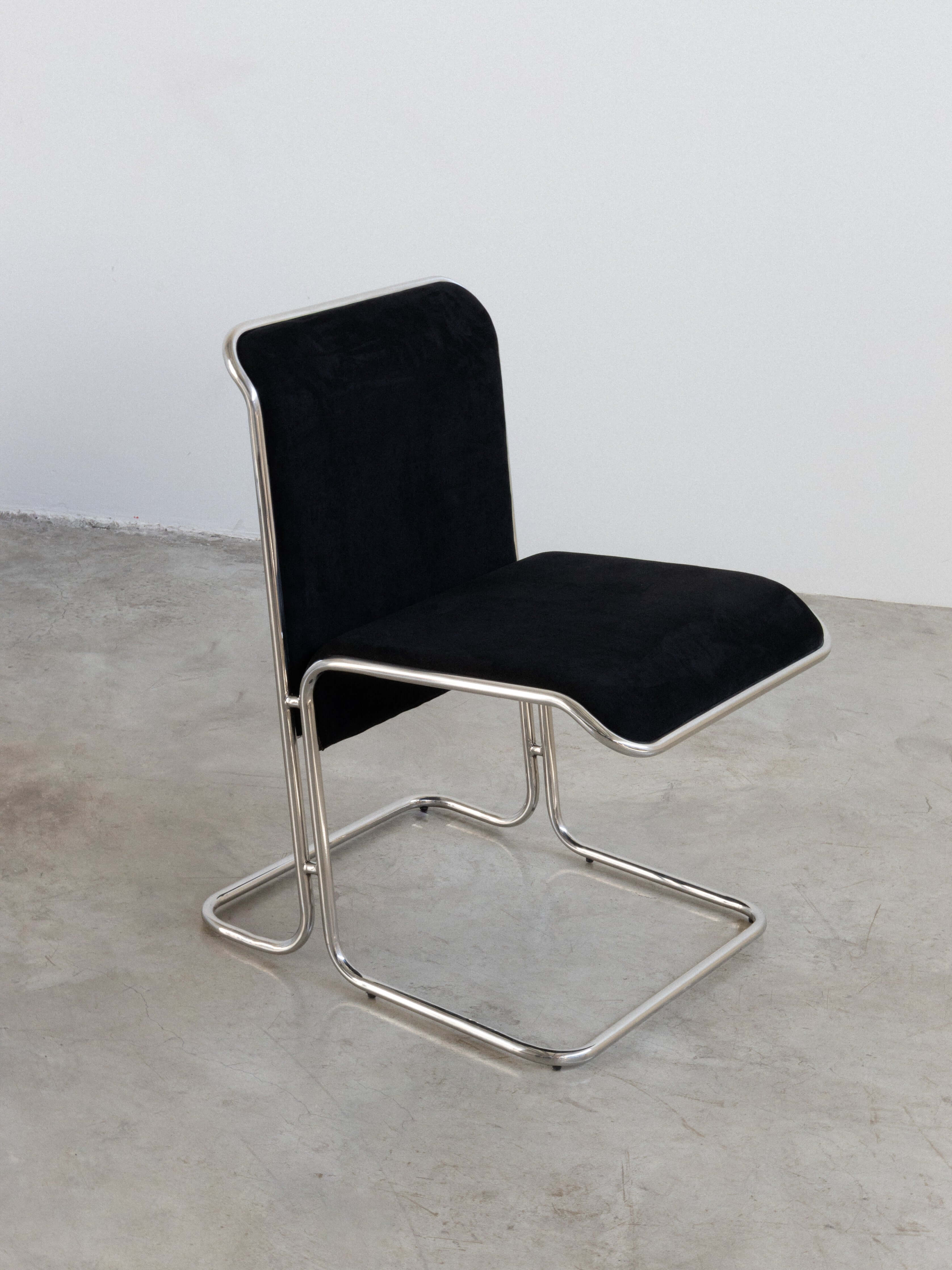 Calla Chair - Black chair with metal frame on a concrete floor and white wall background