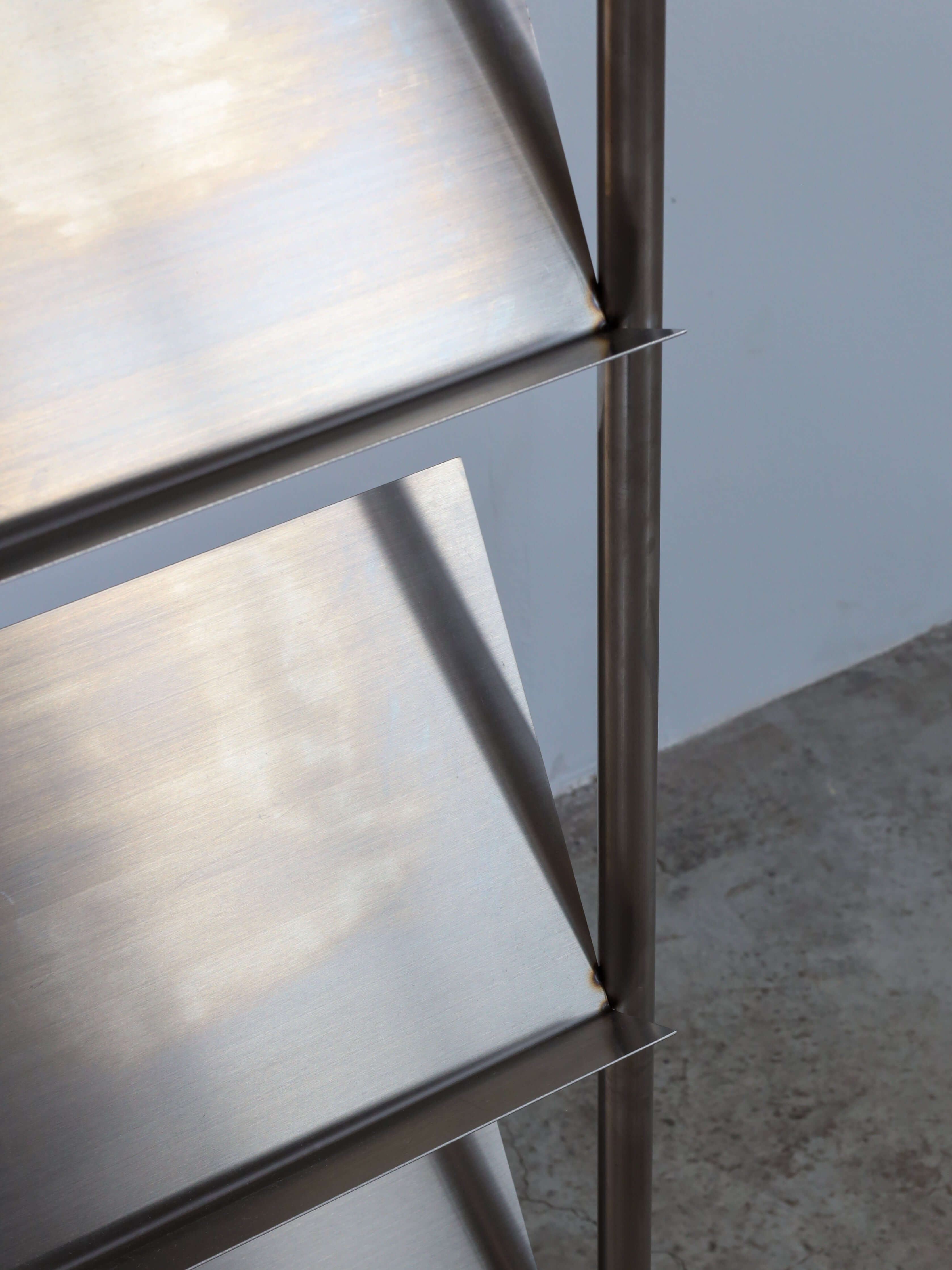 Stainless steel shelving unit with reflective surfaces on a neutral background