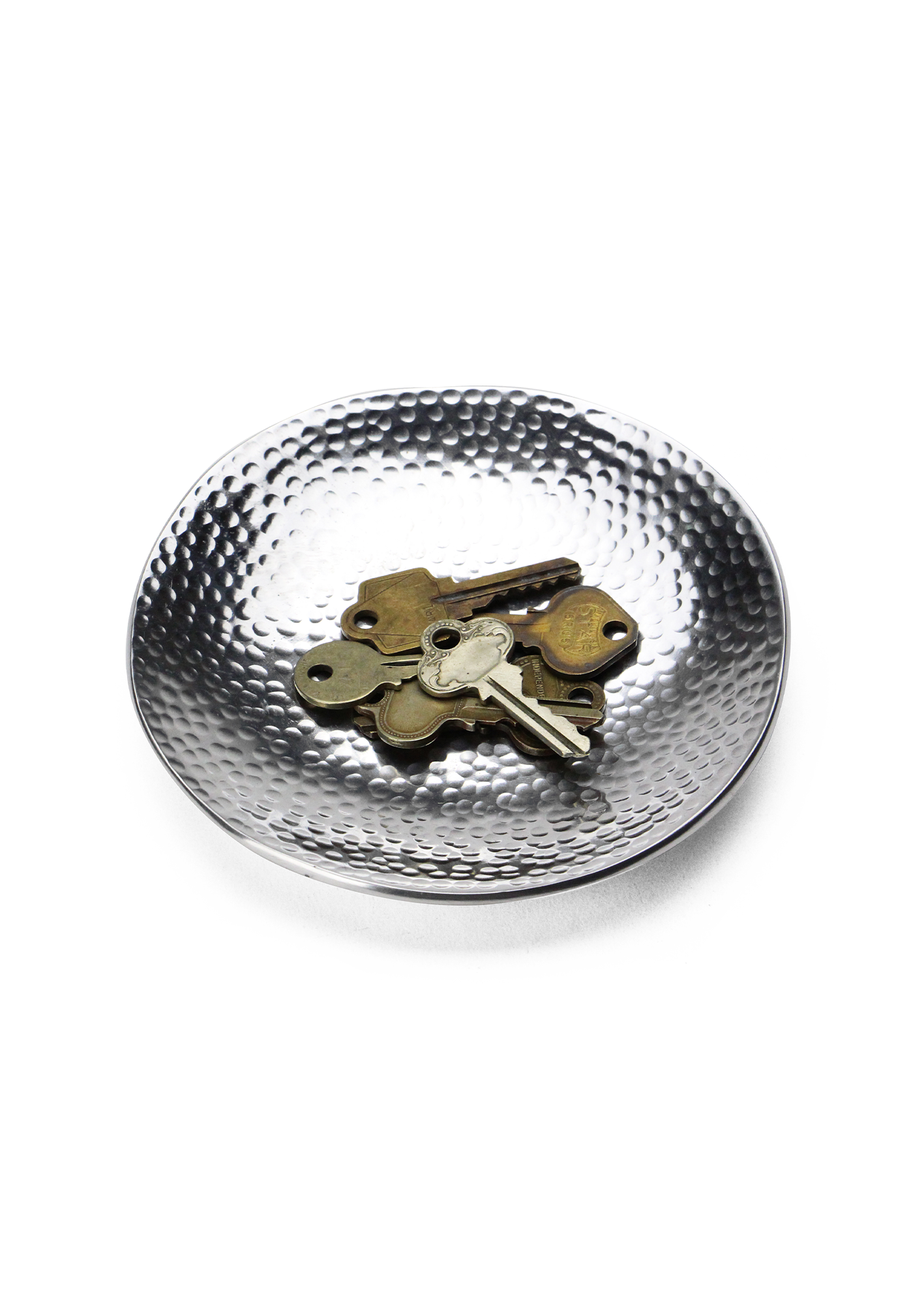 Hammered metal dish with keys on a white background