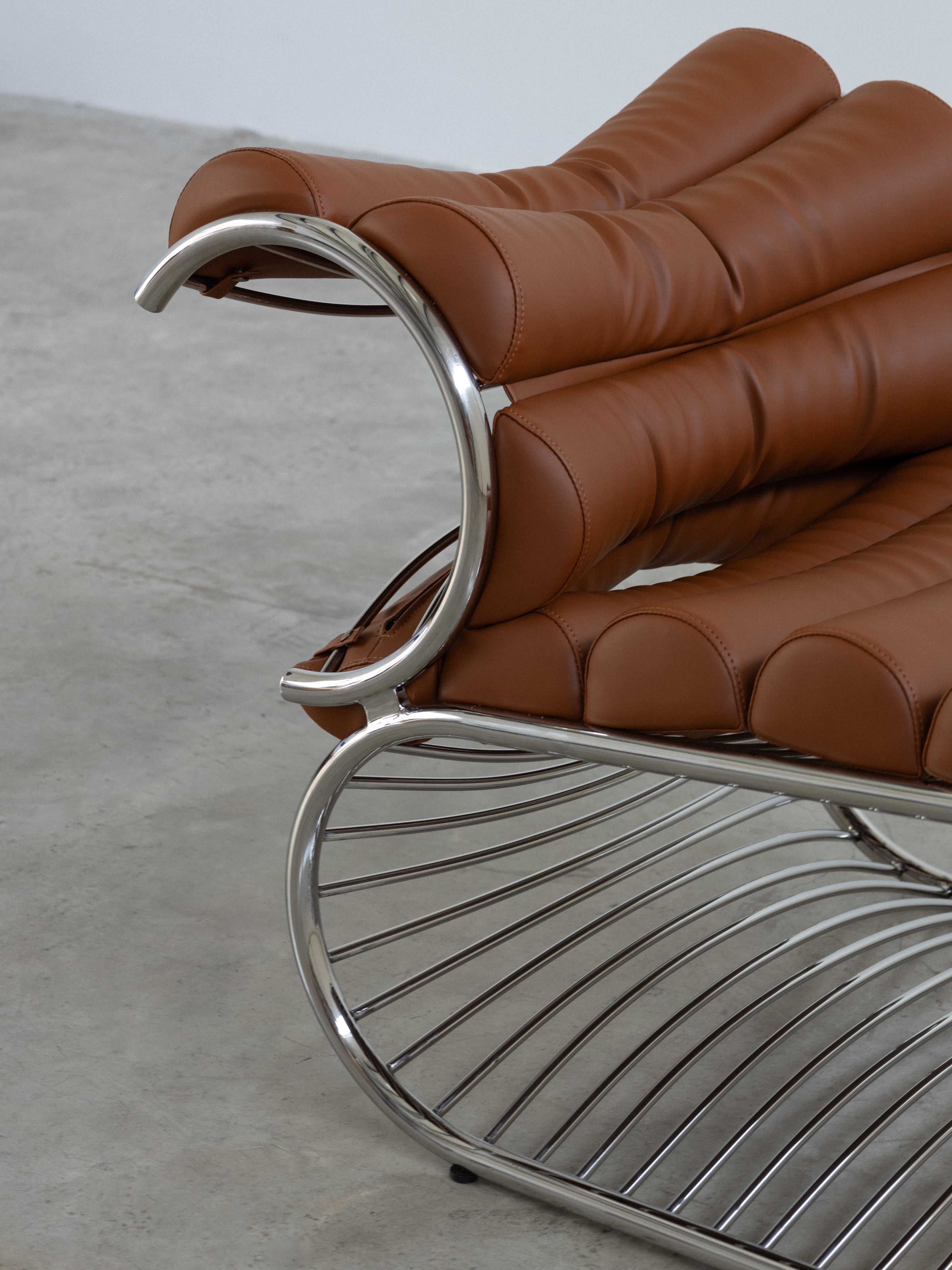 Brown leather chair with metal frame on a gray floor