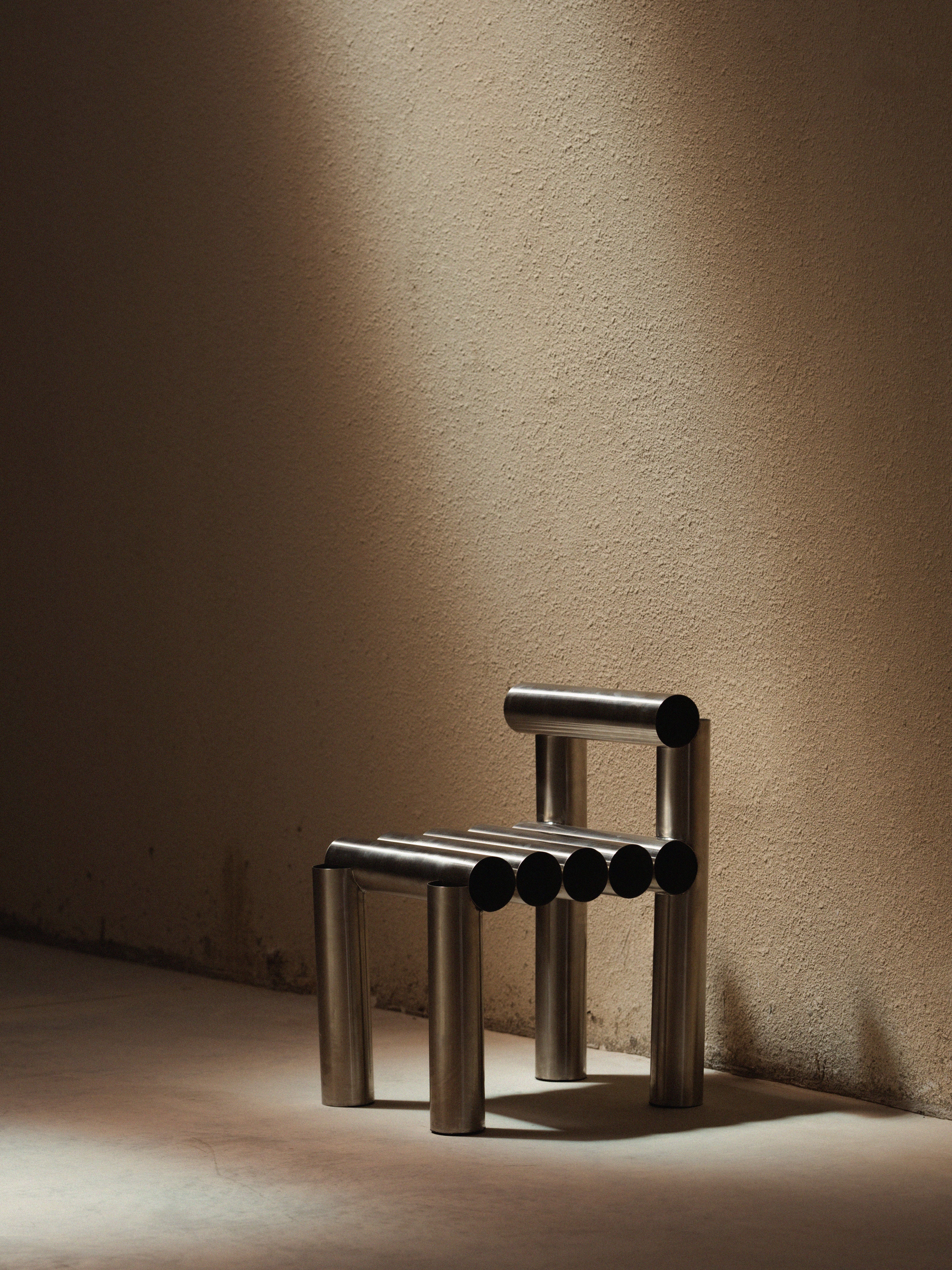 Modern metal chair against a textured beige wall