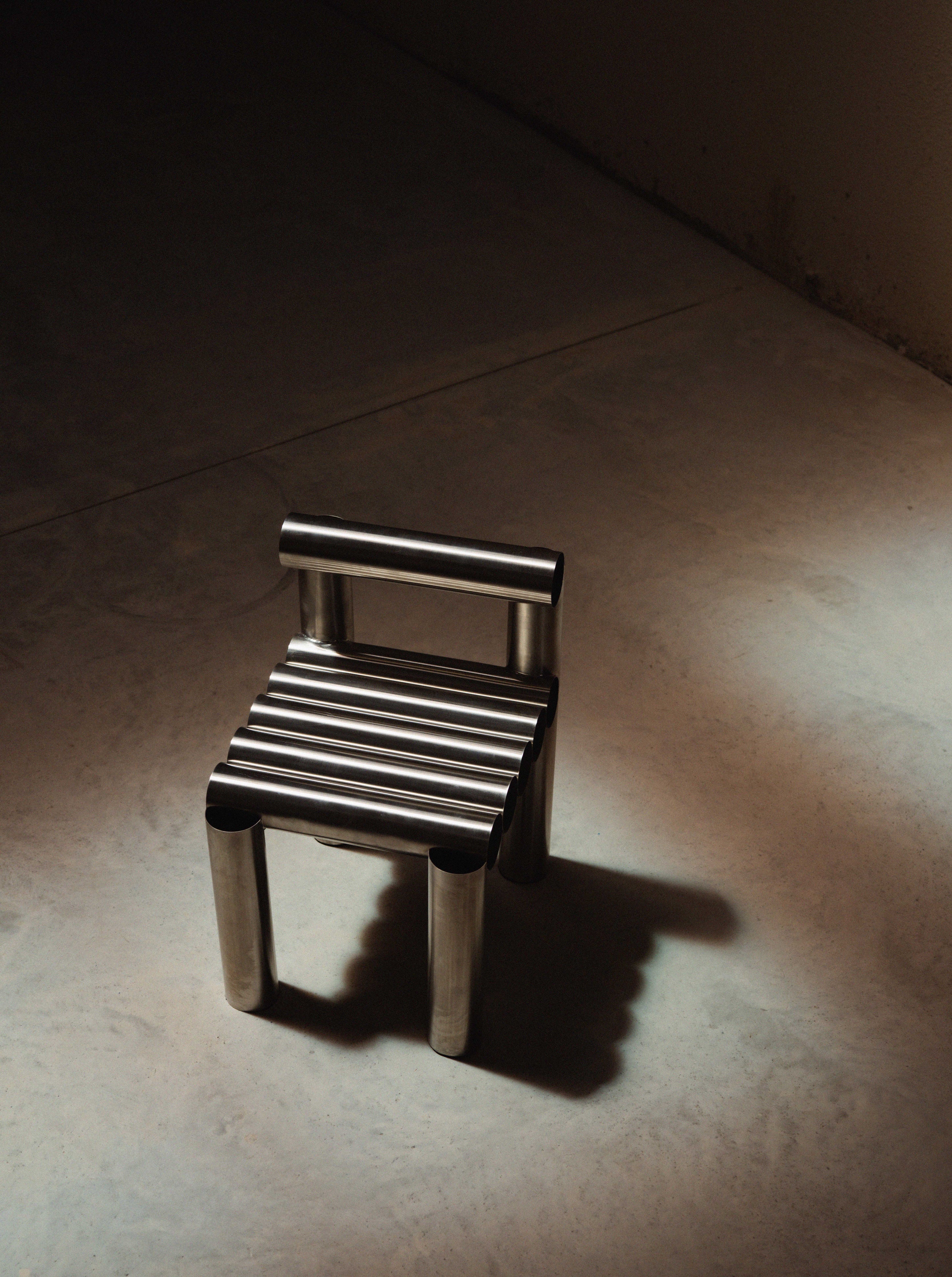 Small metal stool on a textured surface with a dark background