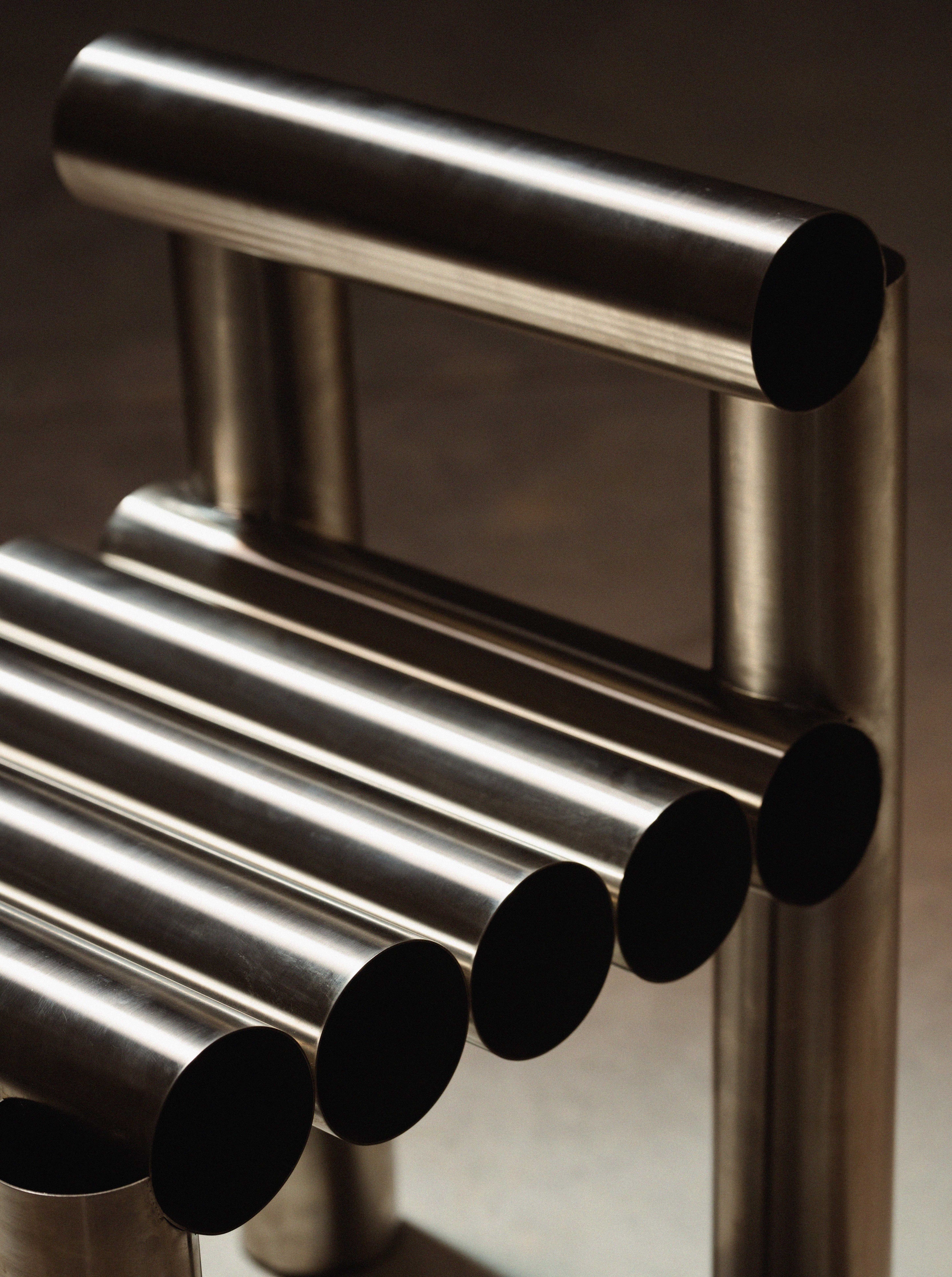Metallic towel rack with cylindrical hooks on a dark background
