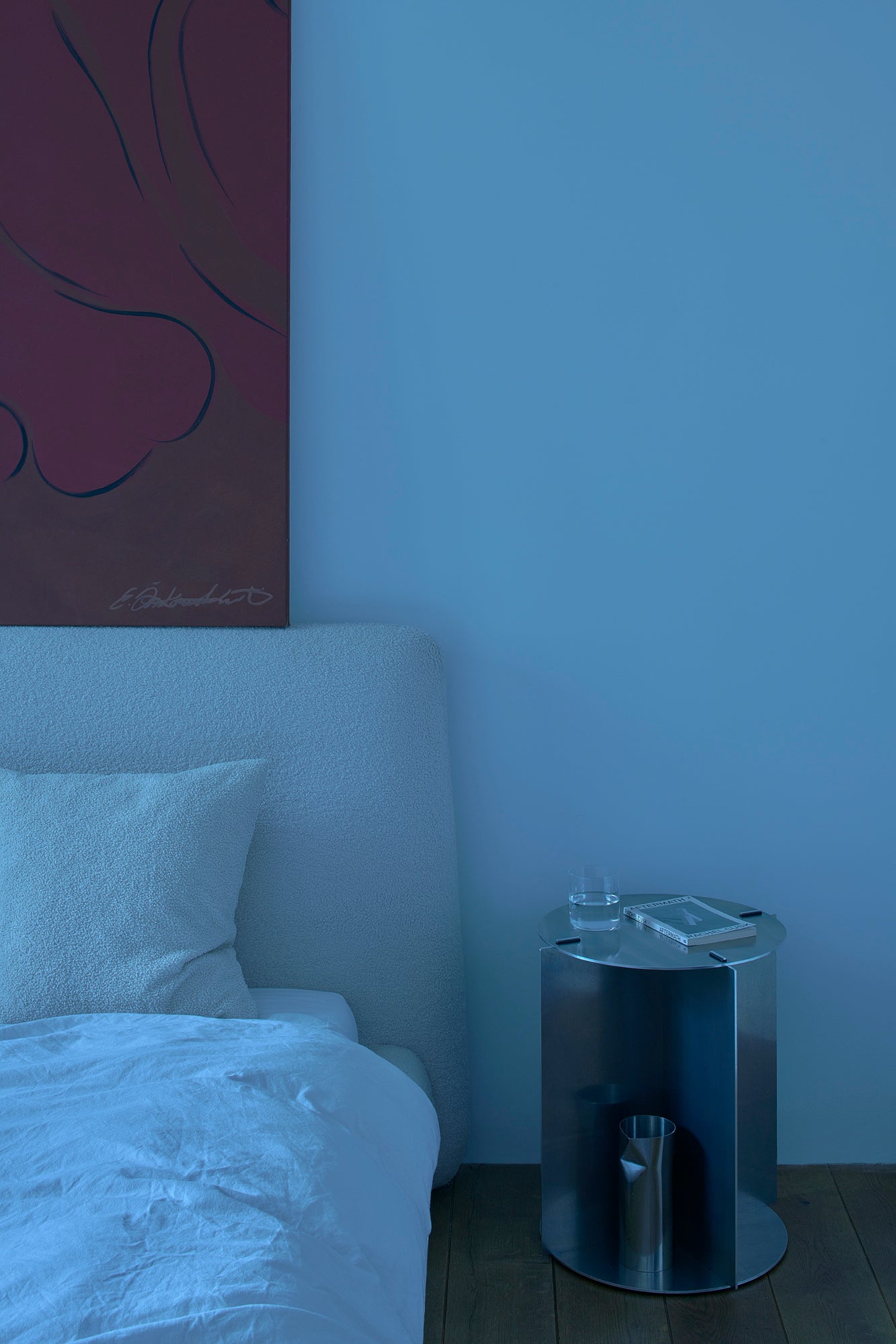 Bedroom with a bed and a nightstand against a blue wall