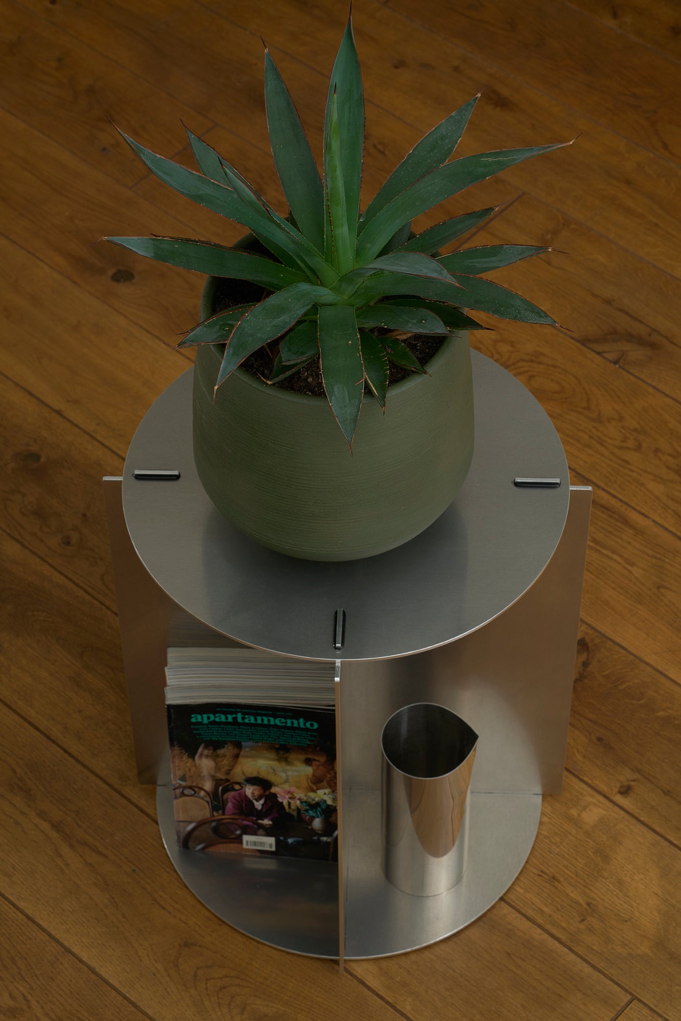 Small round metal table with a potted plant on a wooden floor
