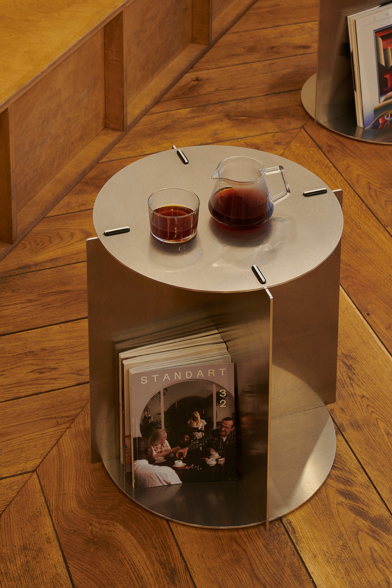 Small round metal table with two glasses of red wine on a wooden floor.