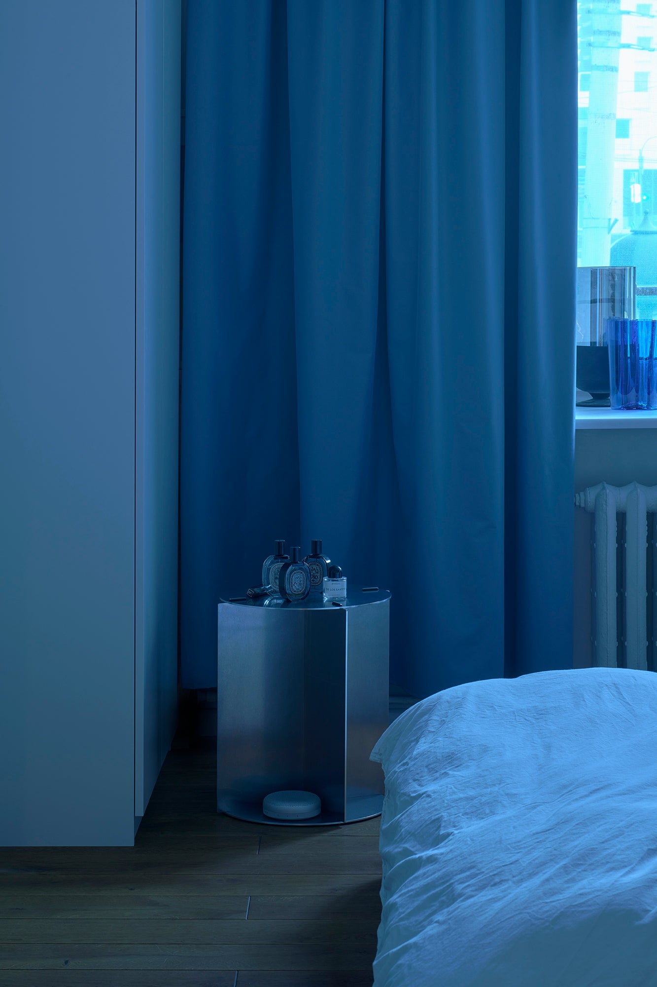 Modern bedroom with a side table and bed in a dimly lit room.