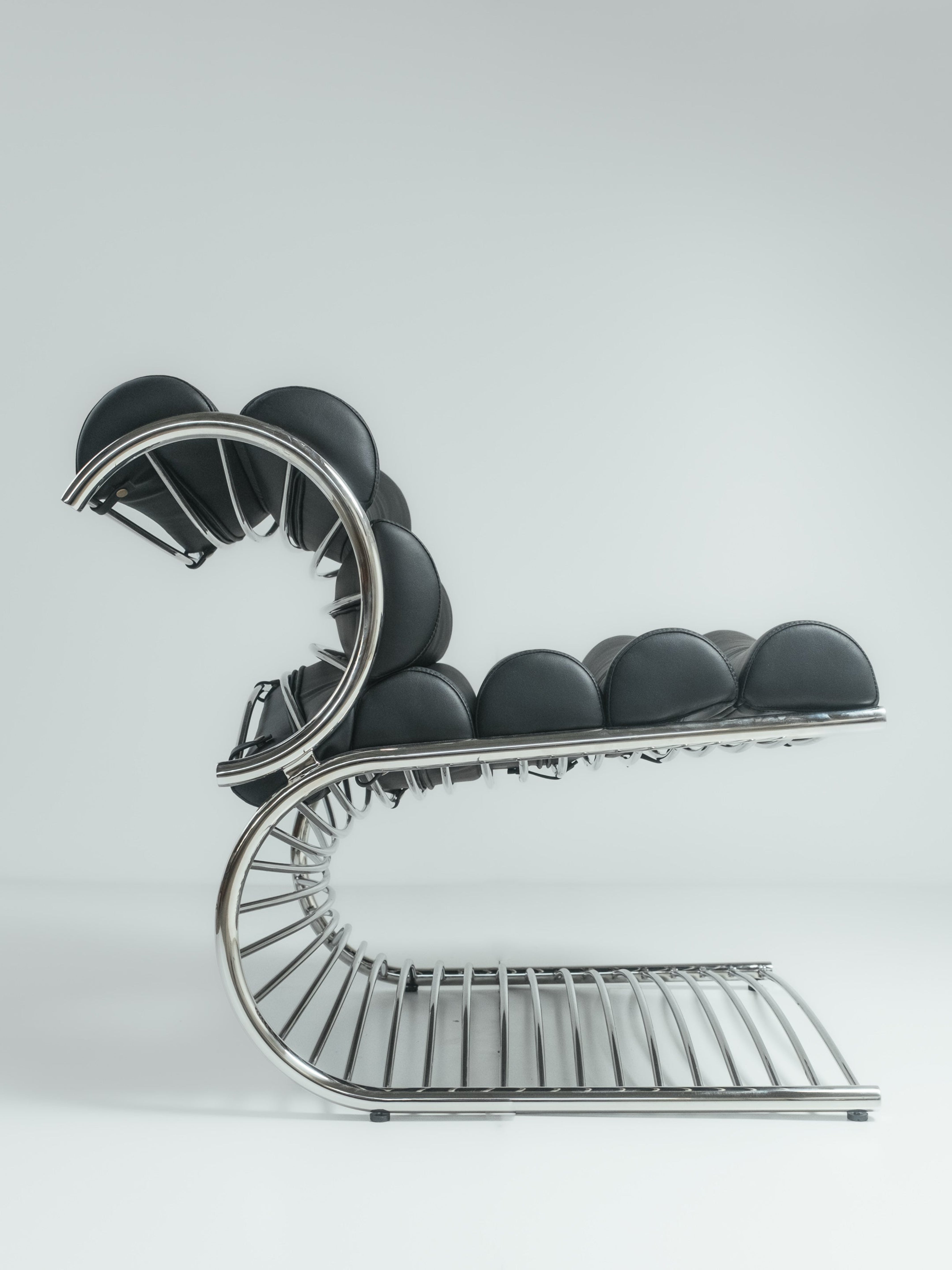 A chair with a unique design, featuring a spiral staircase-like structure with dark-colored padding.