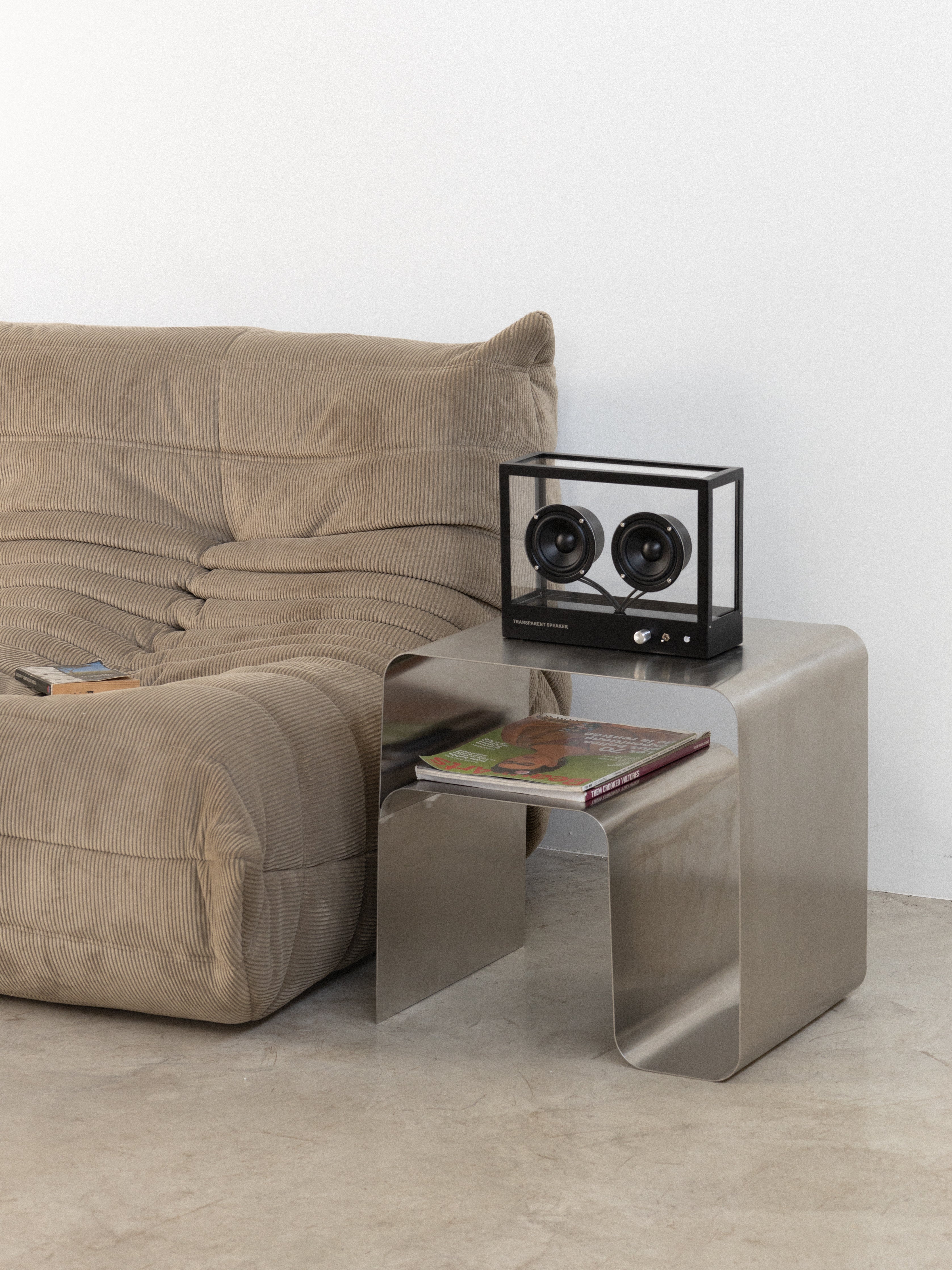 Beige sofa with a modern side table and decorative items on a light gray background