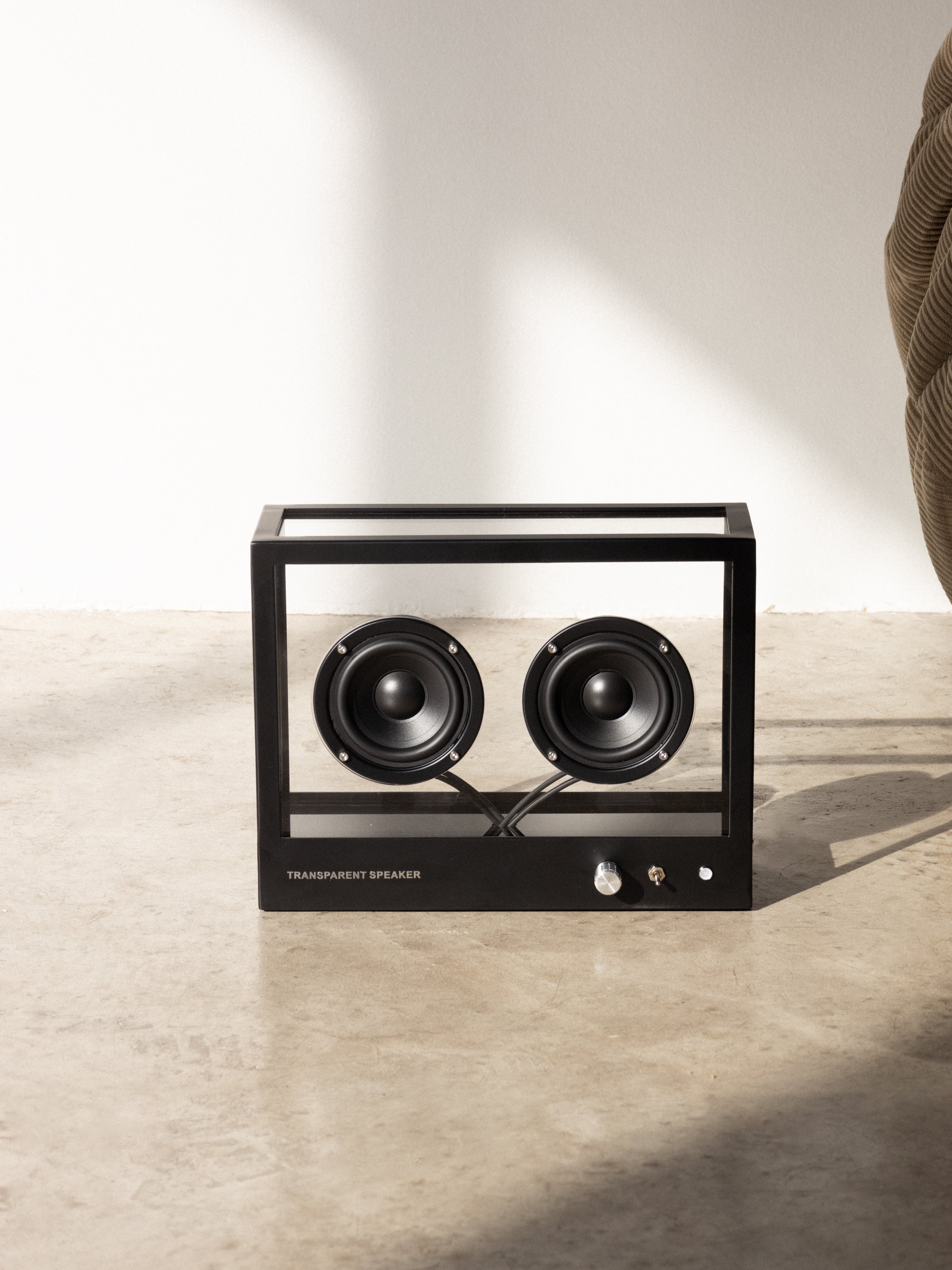 Black and silver speaker on a beige surface with a neutral background