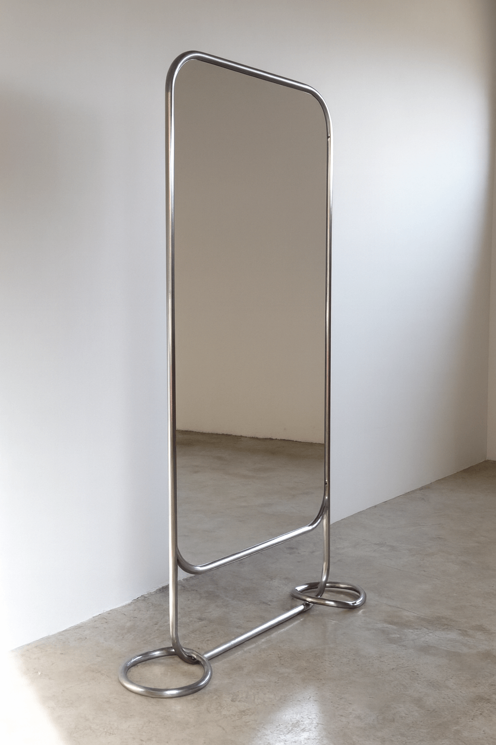 Modern freestanding mirror with stainless steel pipe frame and circular base, ideal for minimalist interiors.