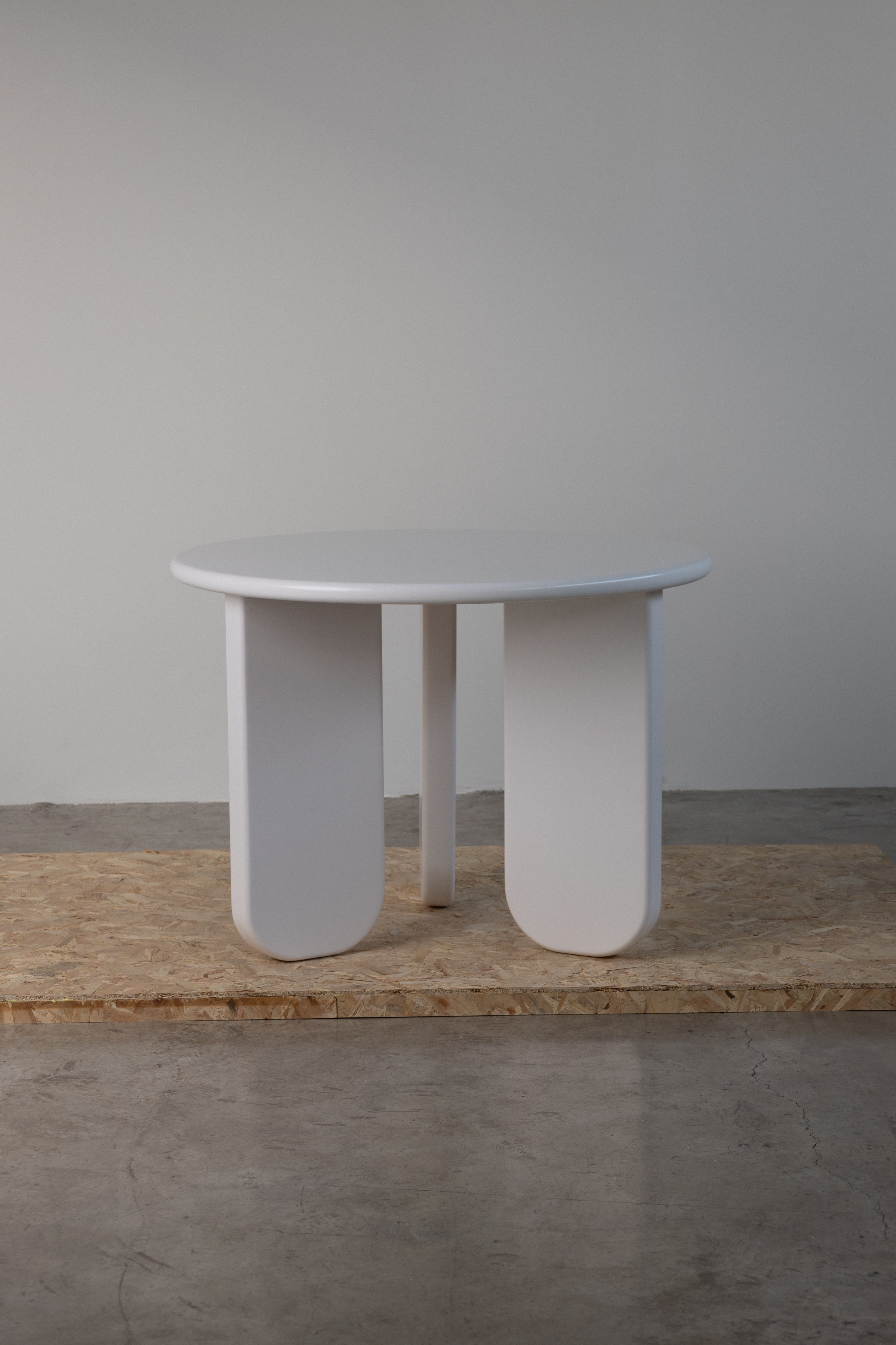 Sculptural Alara Dining Table – White round dining table with bold geometric legs, adding a touch of modern elegance to any dining room.