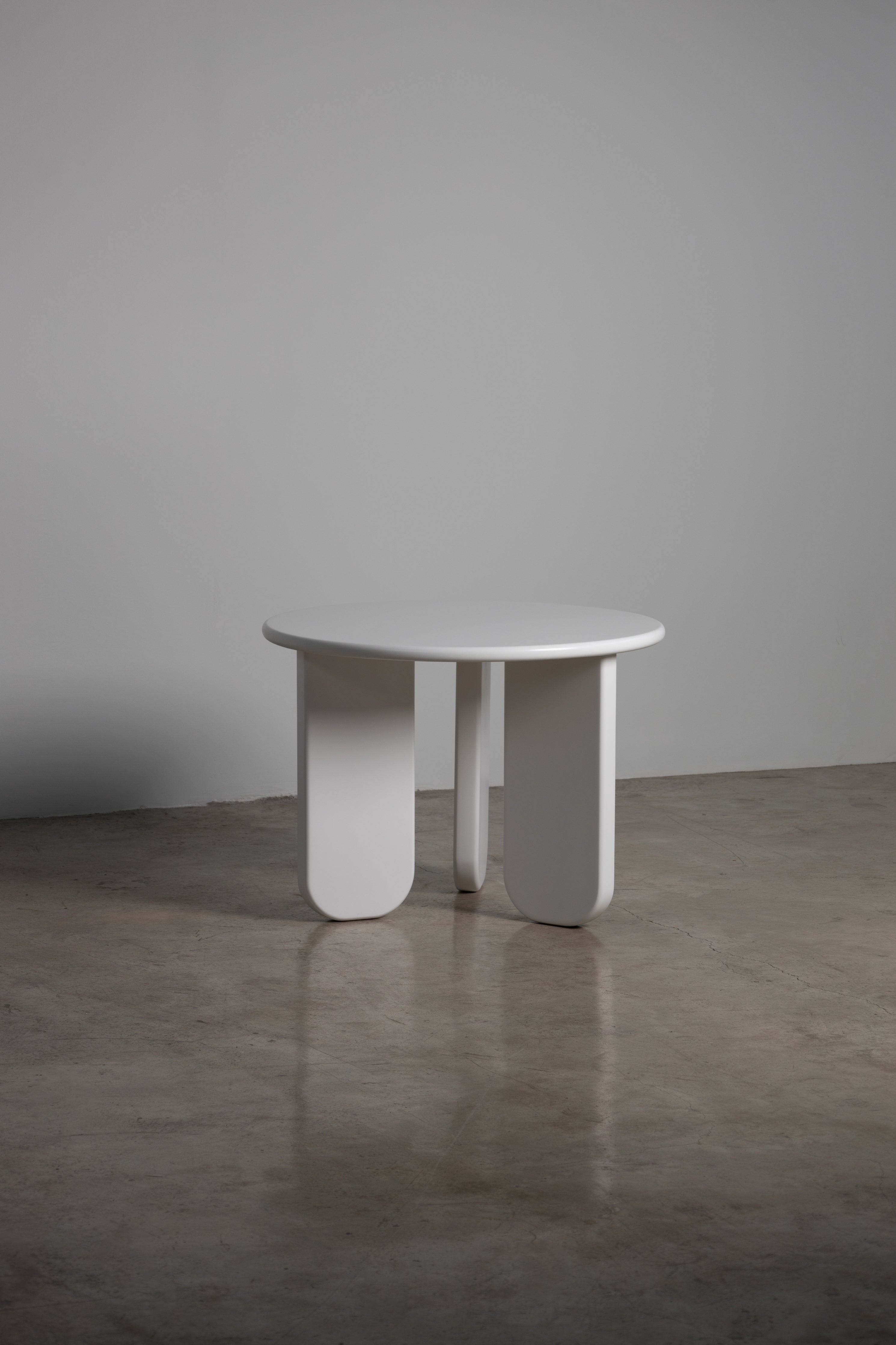 Alara Dining Table – Sculptural round dining table with minimalist white MDF top and bold geometric legs, ideal for modern interiors.