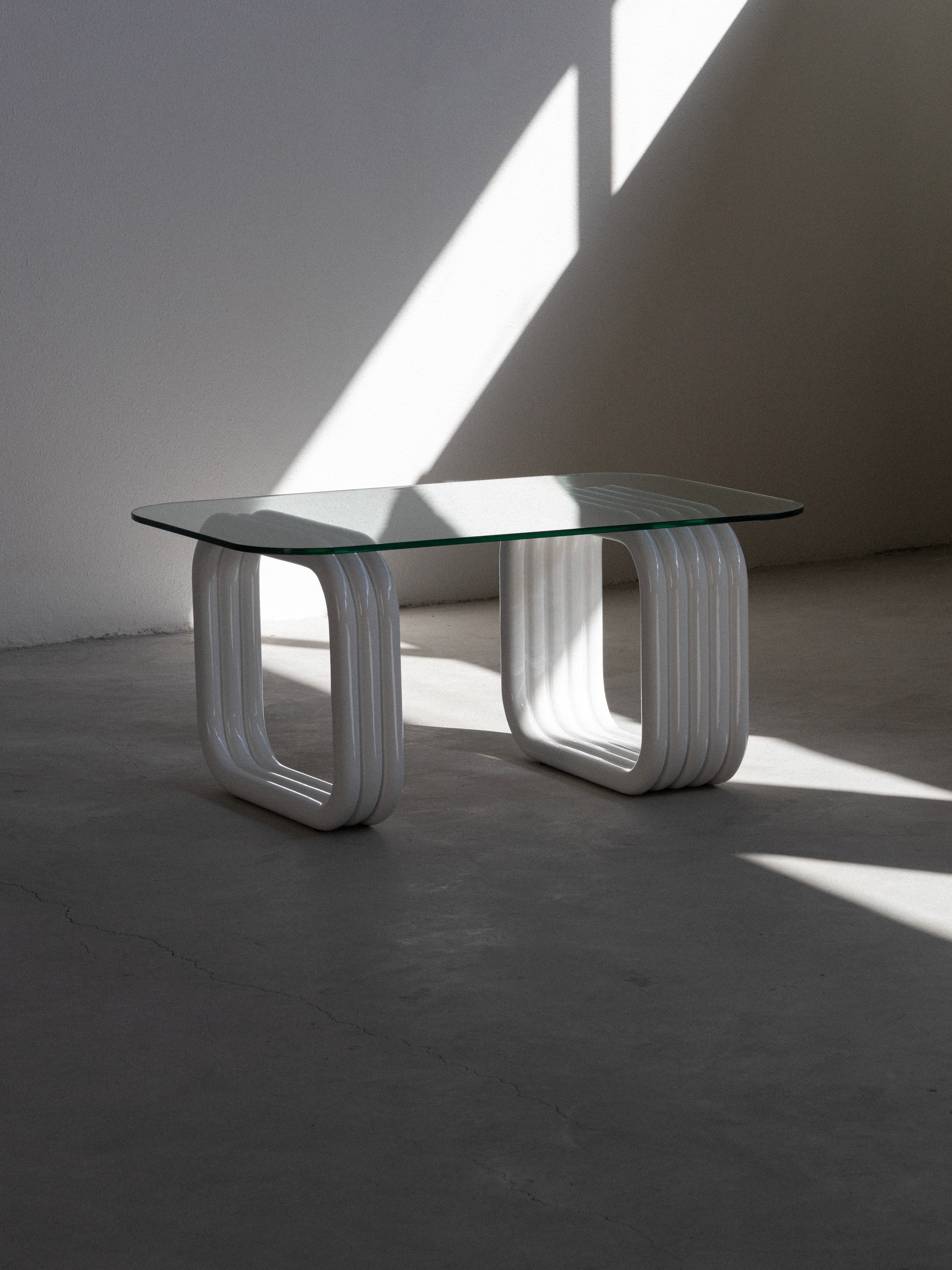 A rectangular glass coffee table with white, curved leg frames.