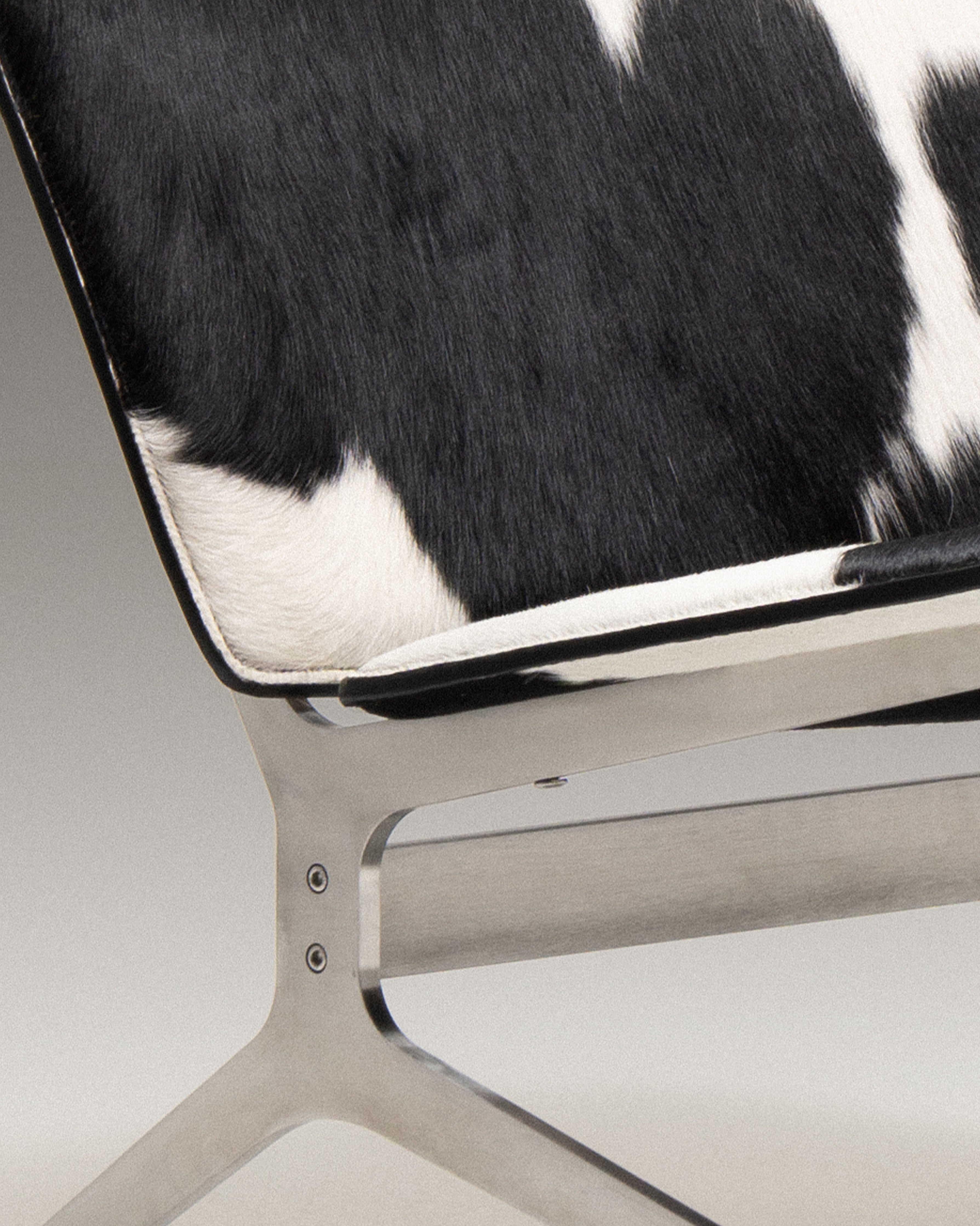 Detail of Kay Lounge Chair showcasing the black and white fur upholstery and sleek metal frame.