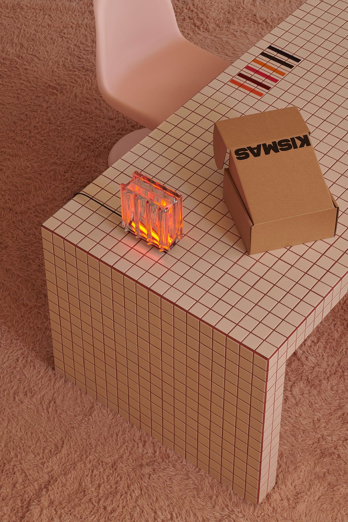 Small table with a cardboard box labeled 'Kismas' and a small fire pit on a tiled surface.