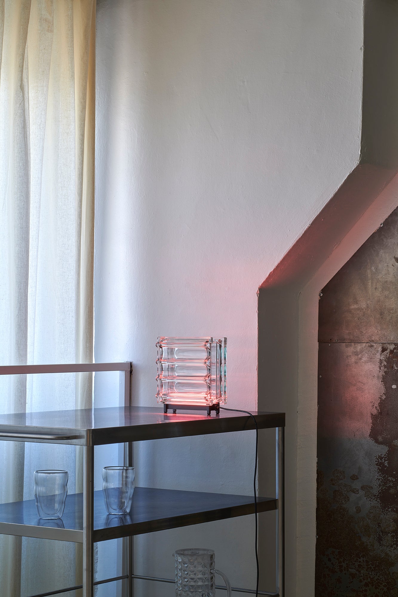 Modern interior with a glass table and decorative lamp against a white wall.