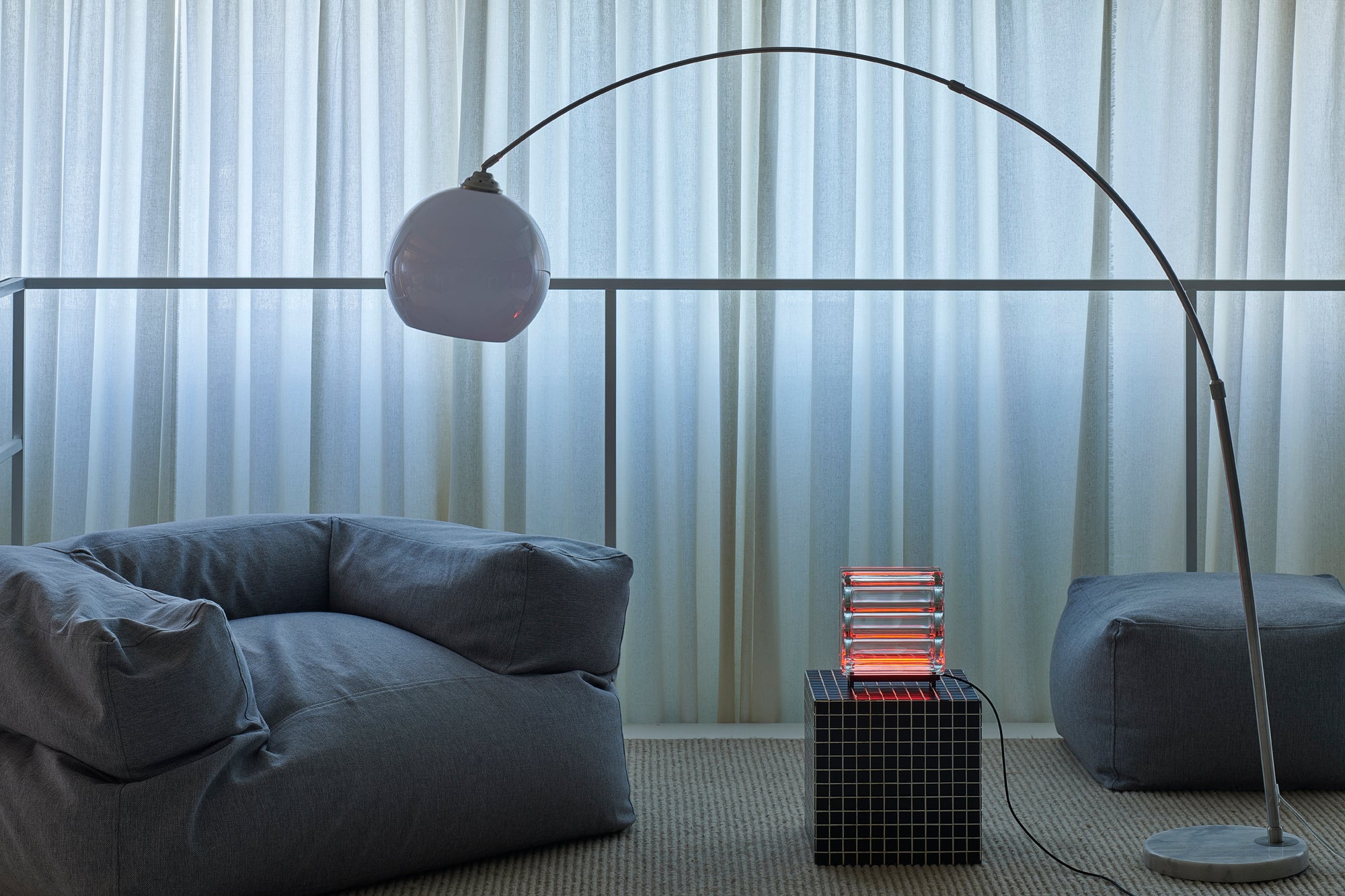 Modern living room with a floor lamp, sofa, and side table against a curtain backdrop