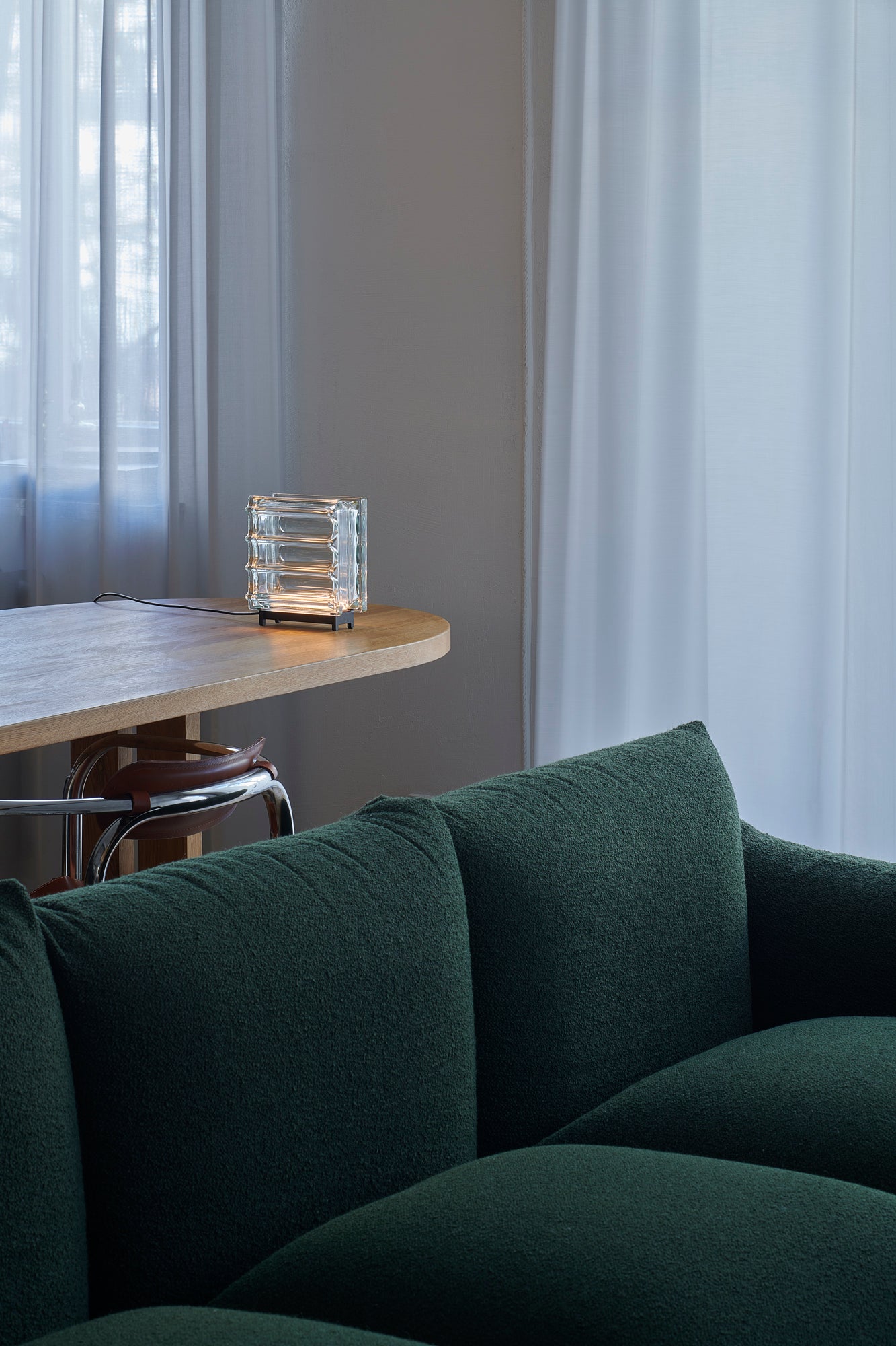 Green sofa in a room with a wooden table and glass decorative item.