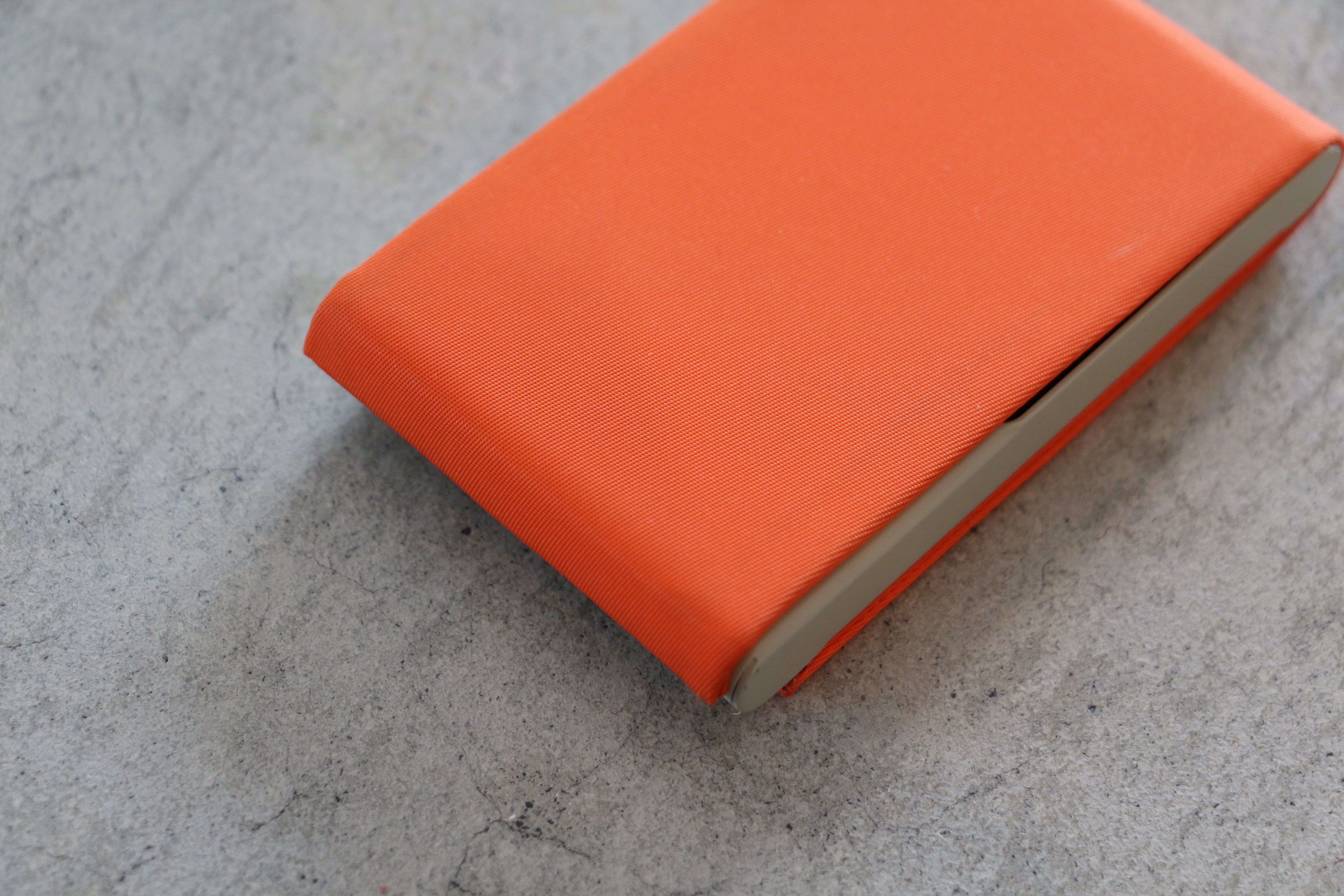 A red card case with a plain design and a visible zipper.