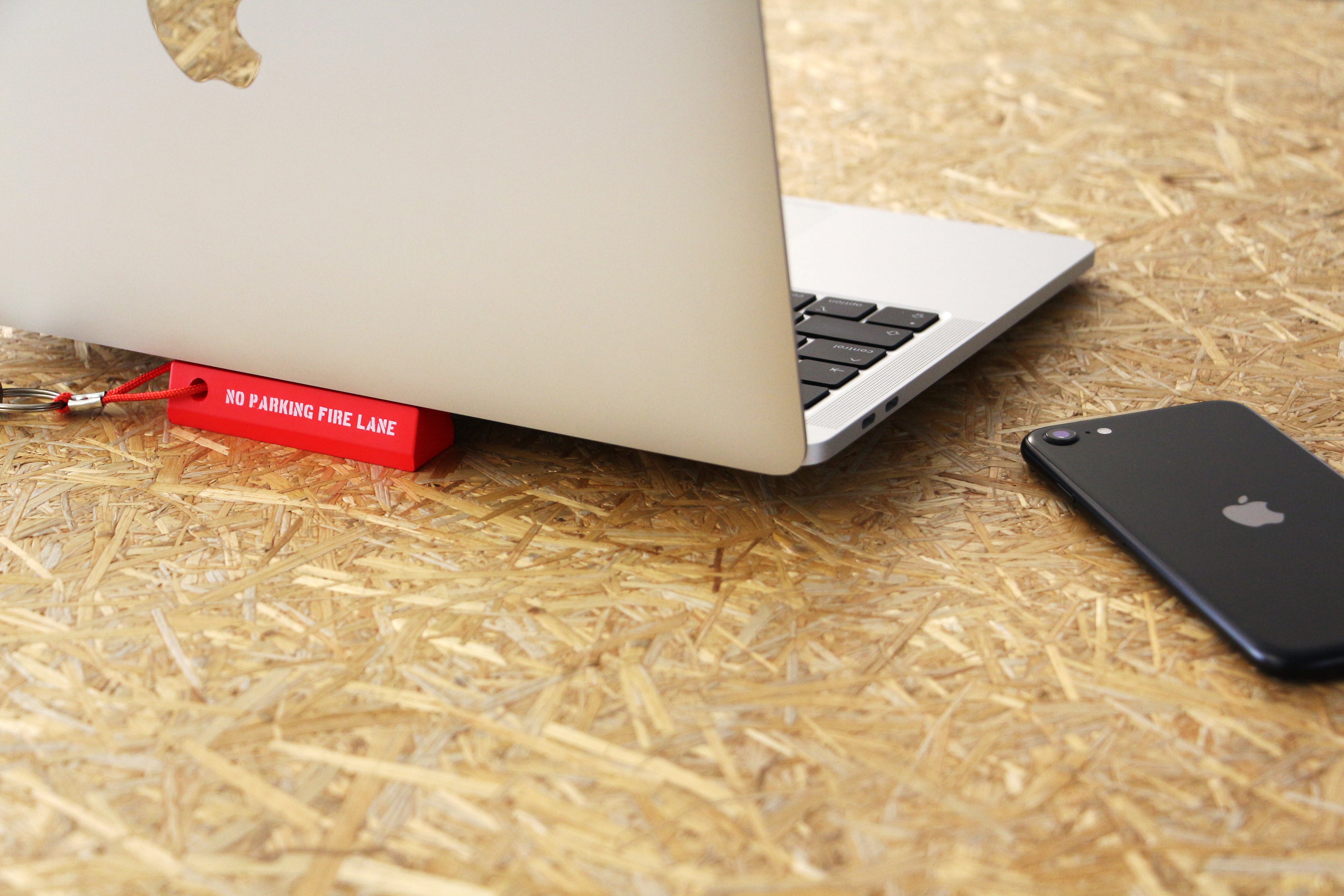 Parking Curb Keyring placed under a laptop on a desk next to a smartphone.