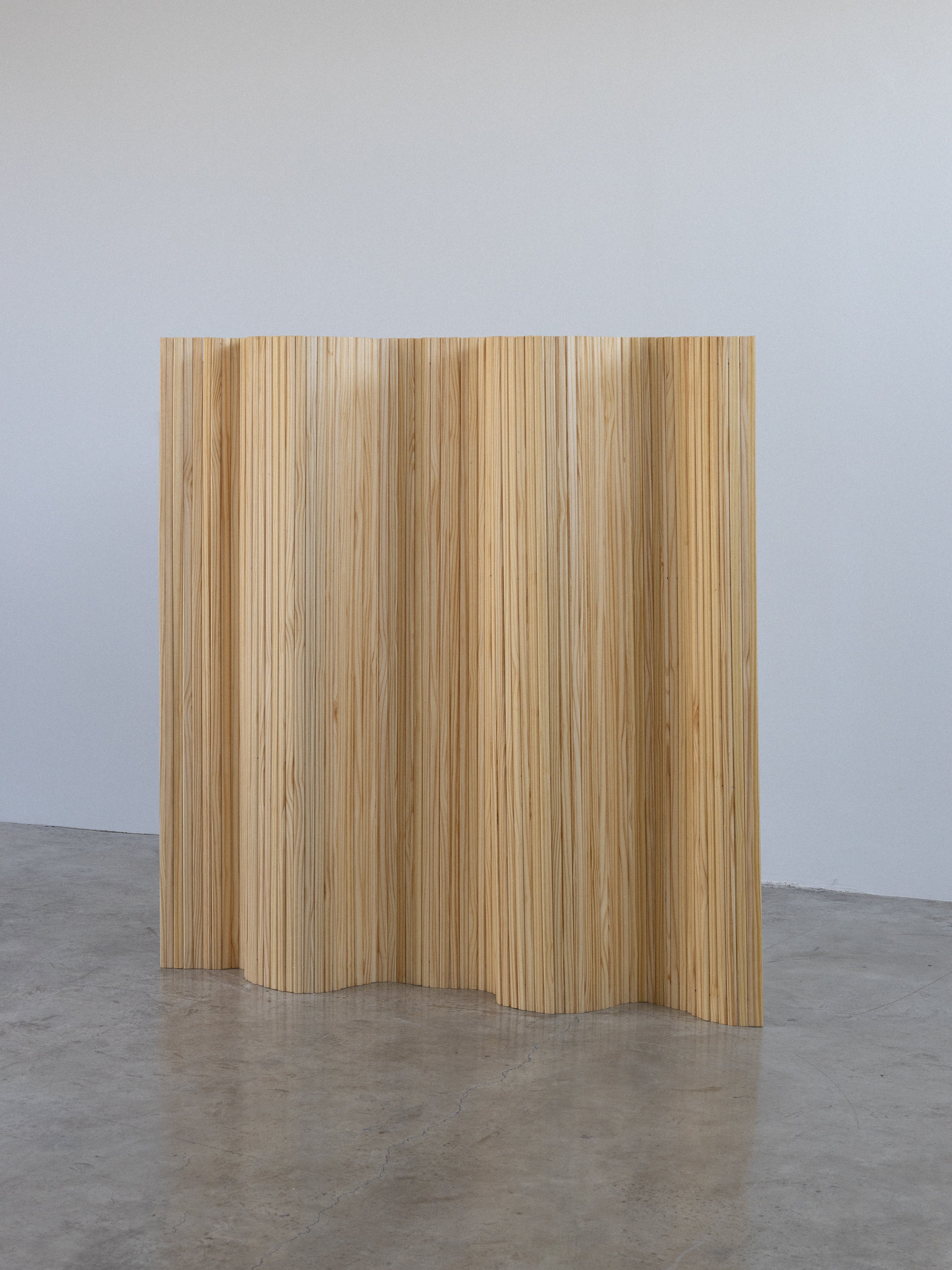 A wooden room divider with a wavy pattern.