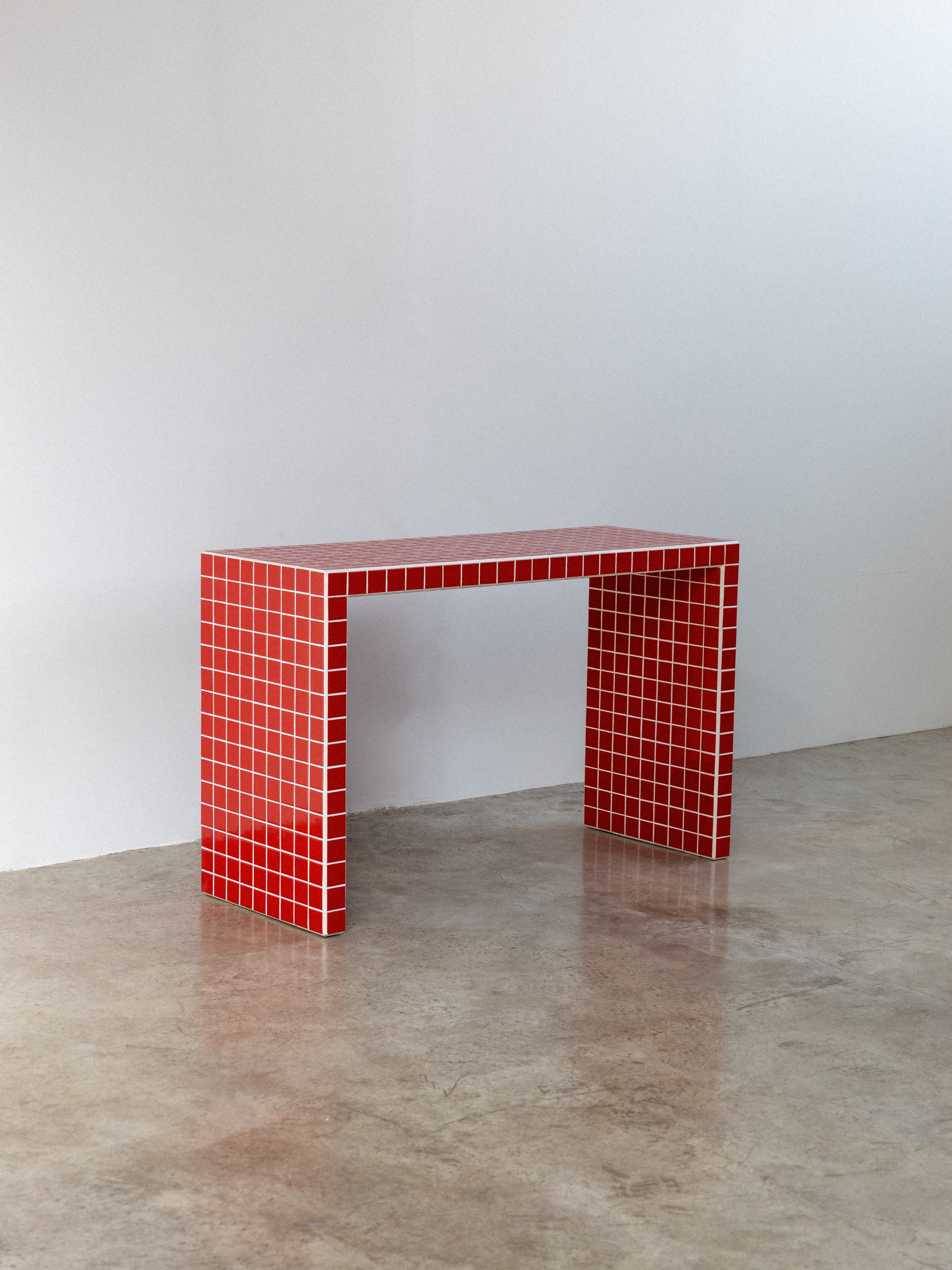 Red tiled table against a white wall on a concrete floor