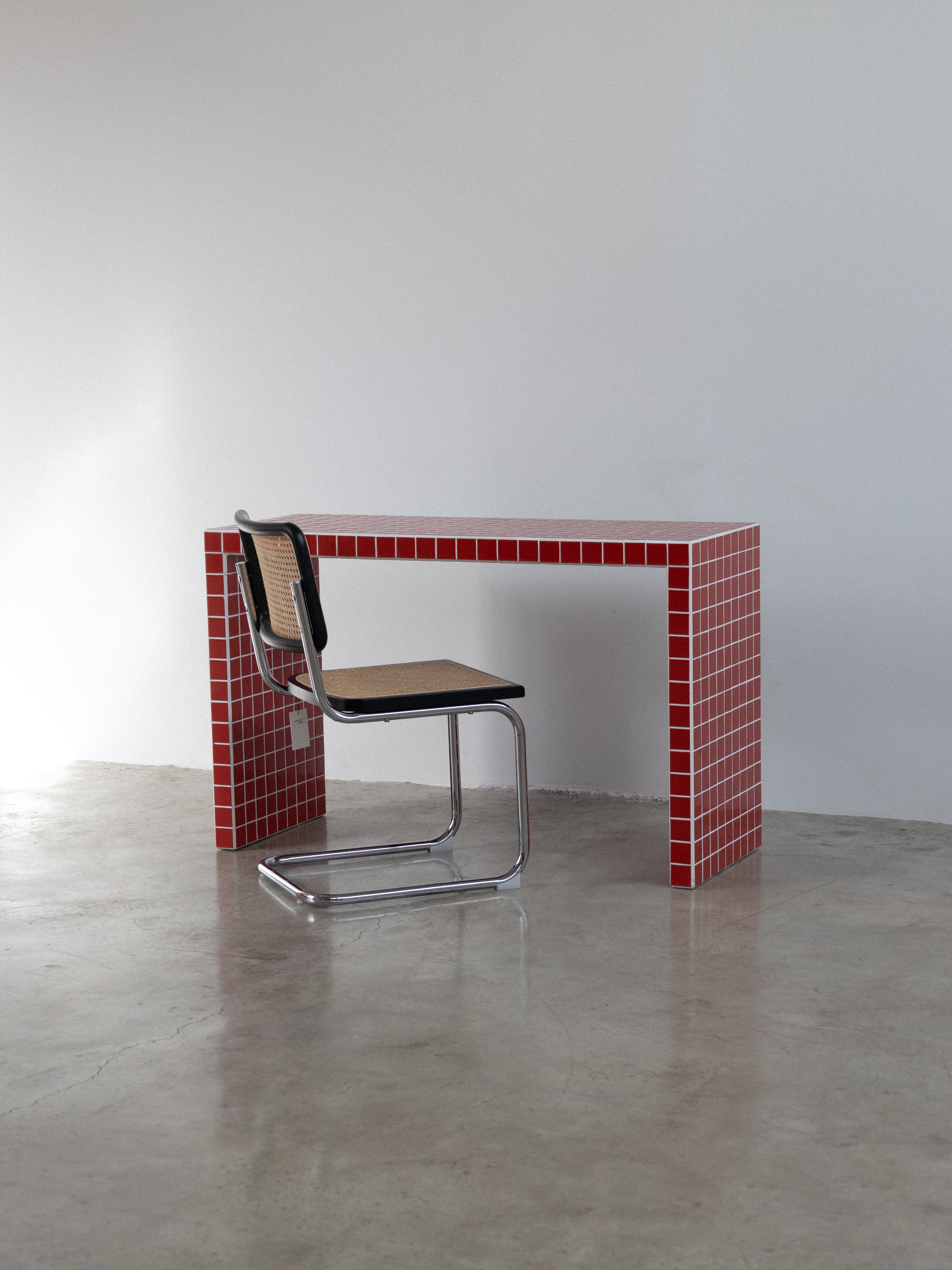 Modern chair in front of a red tiled wall with a white background